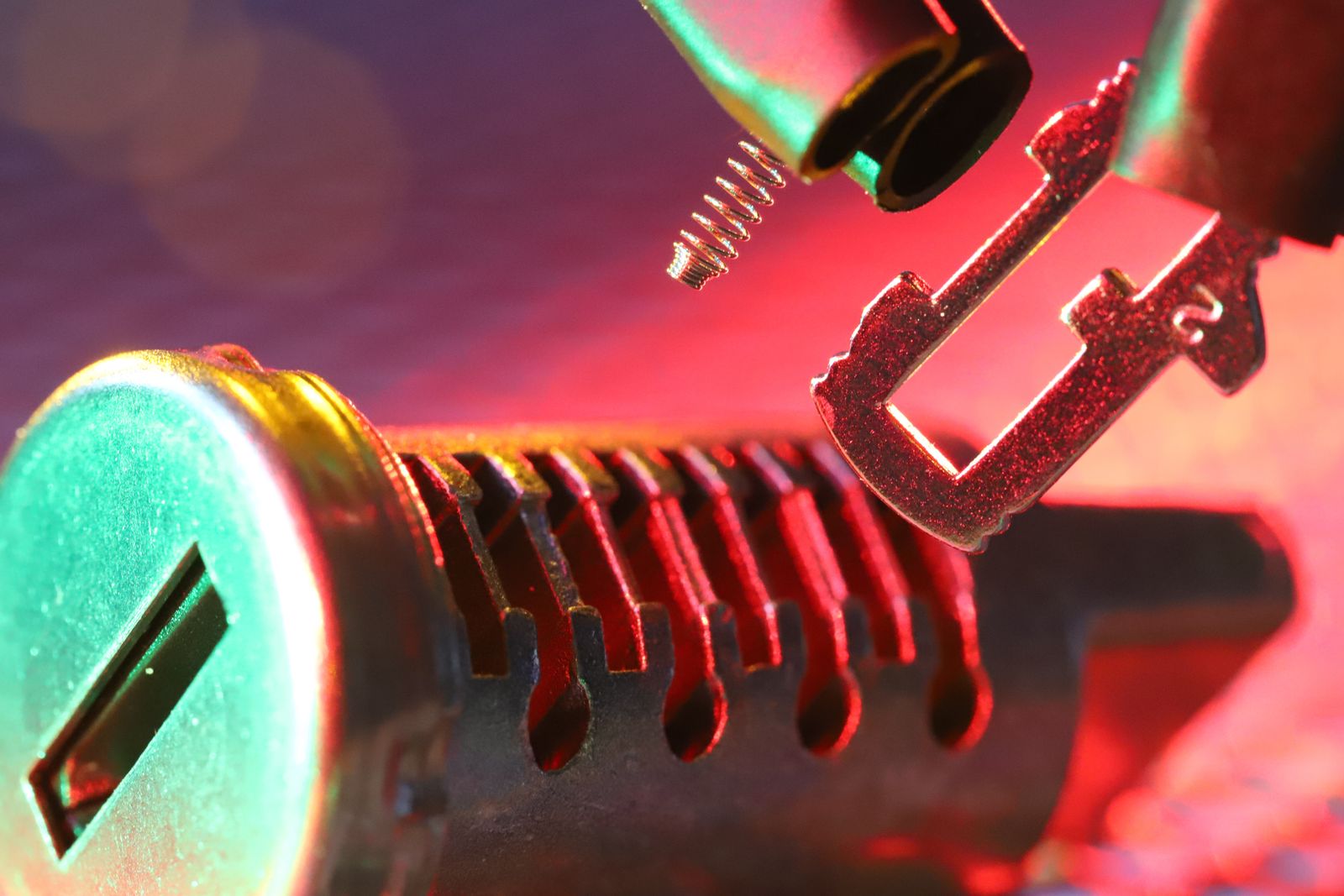 Foto macro de um cilindro de fechadura mecânico e chave, destacando componentes detalhados sob iluminação vibrante.